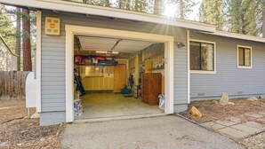 En enplansbyggnad med en garageingång, en liten veranda och ett synligt förvaringsutrymme med diverse föremål.
