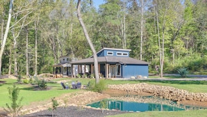 A house with a pond, surrounded by trees and a stone wall. - Waterfront 'blue Spruce' Small Home in Wildwood! (Wildwood)