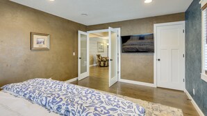 A bedroom with a bed, a door leading to another room, and a framed picture on the wall. - Getaway w/ Private Acreage in the Minneapolis Area (Loretto)