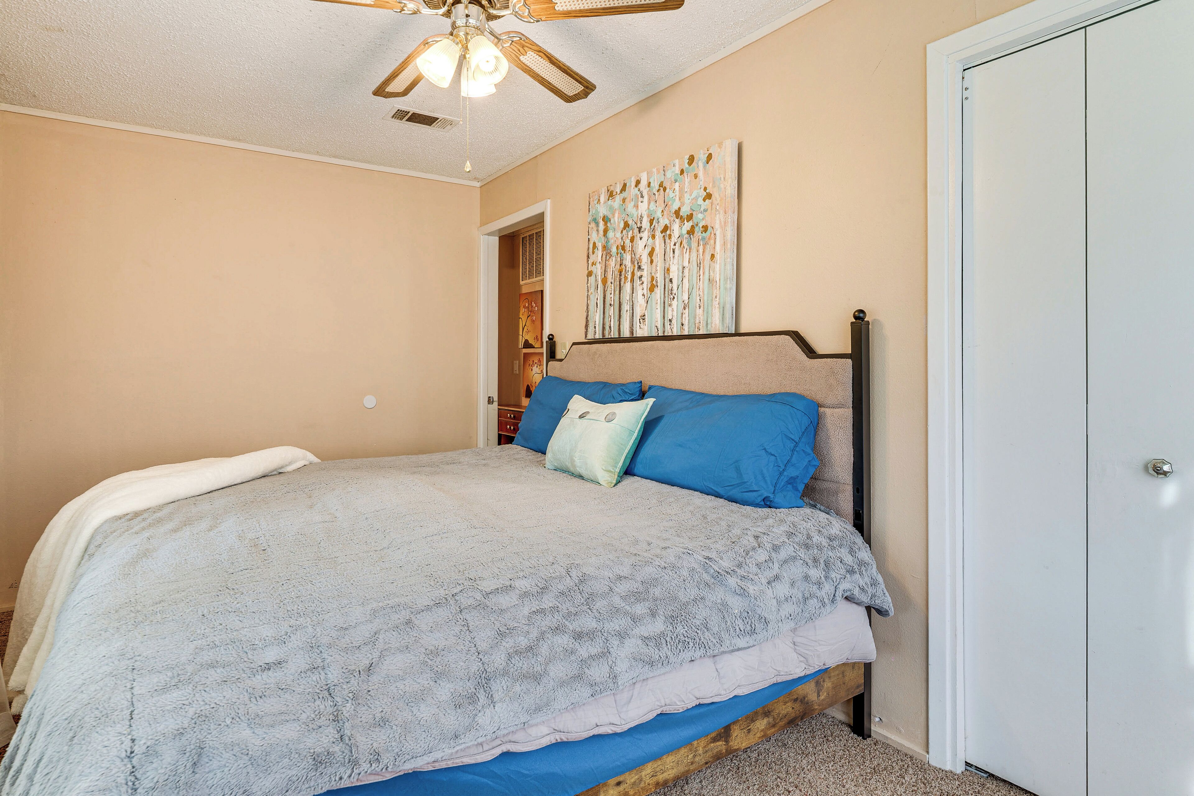 A bedroom with a bed, a ceiling fan, and a door.