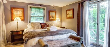 A bedroom with a bed, a bench, a ceiling fan, and a view through a window.