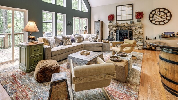 A spacious living room with a sectional sofa, a fireplace, and large windows. - Modern Mountain Zen 3-bed, 3-bath Home With Creeks (Sapphire)