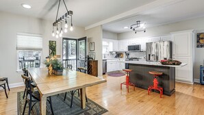 A modern kitchen with white cabinets, a stainless steel refrigerator, and a wooden dining table with chairs. - Modern Mountain Zen 3-bed, 3-bath Home With Creeks (Sapphire)