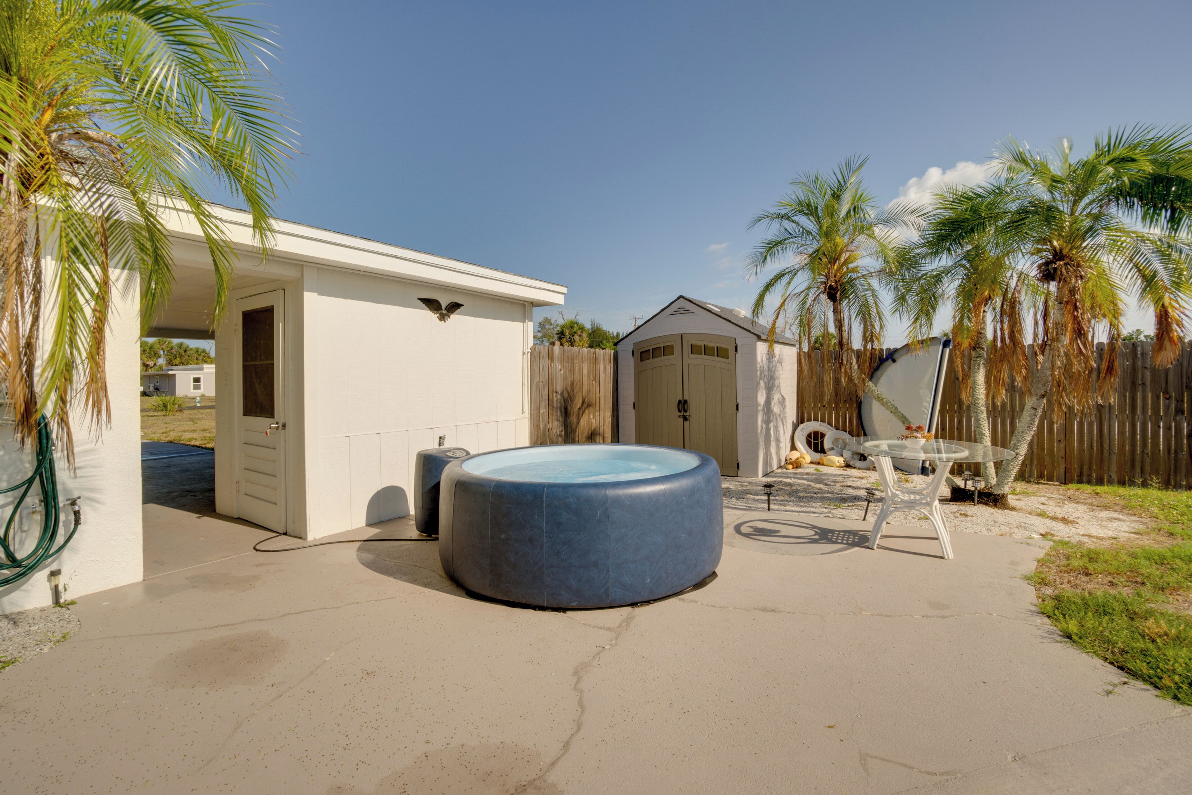 A backyard with a swimming pool, a covered patio, and a garage.