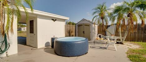A backyard with a swimming pool, a covered patio, and a garage.