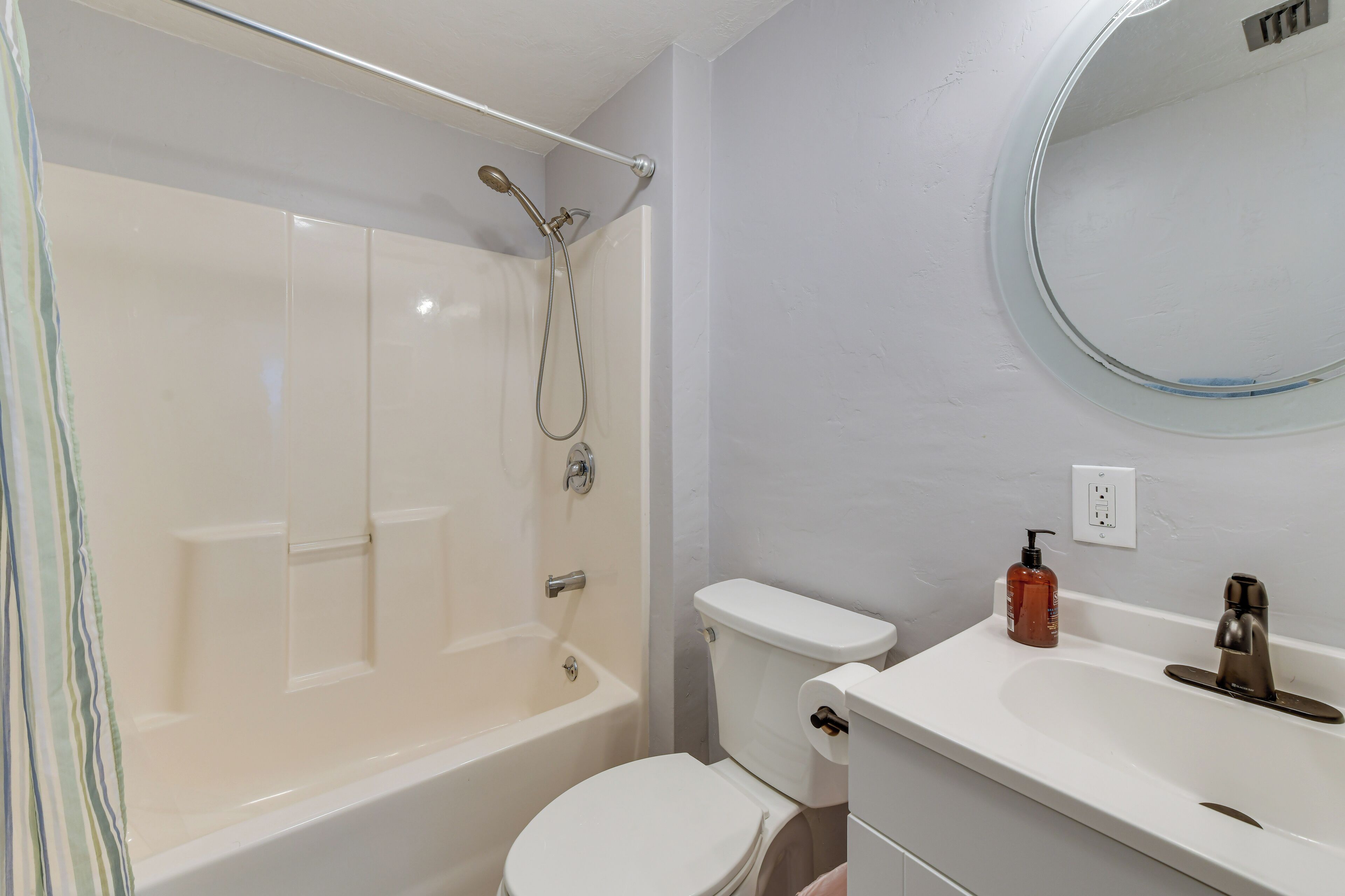 A bathroom with a bathtub, toilet, sink, and a mirror.