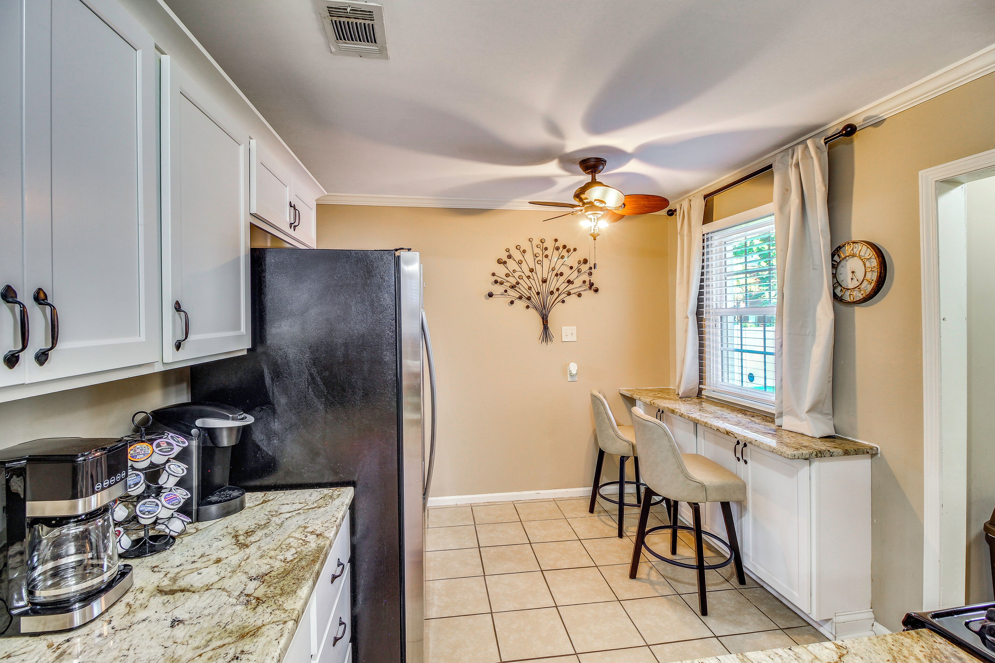 A kitchen with white cabinets, a black refrigerator, a coffee maker, and a wall clock.