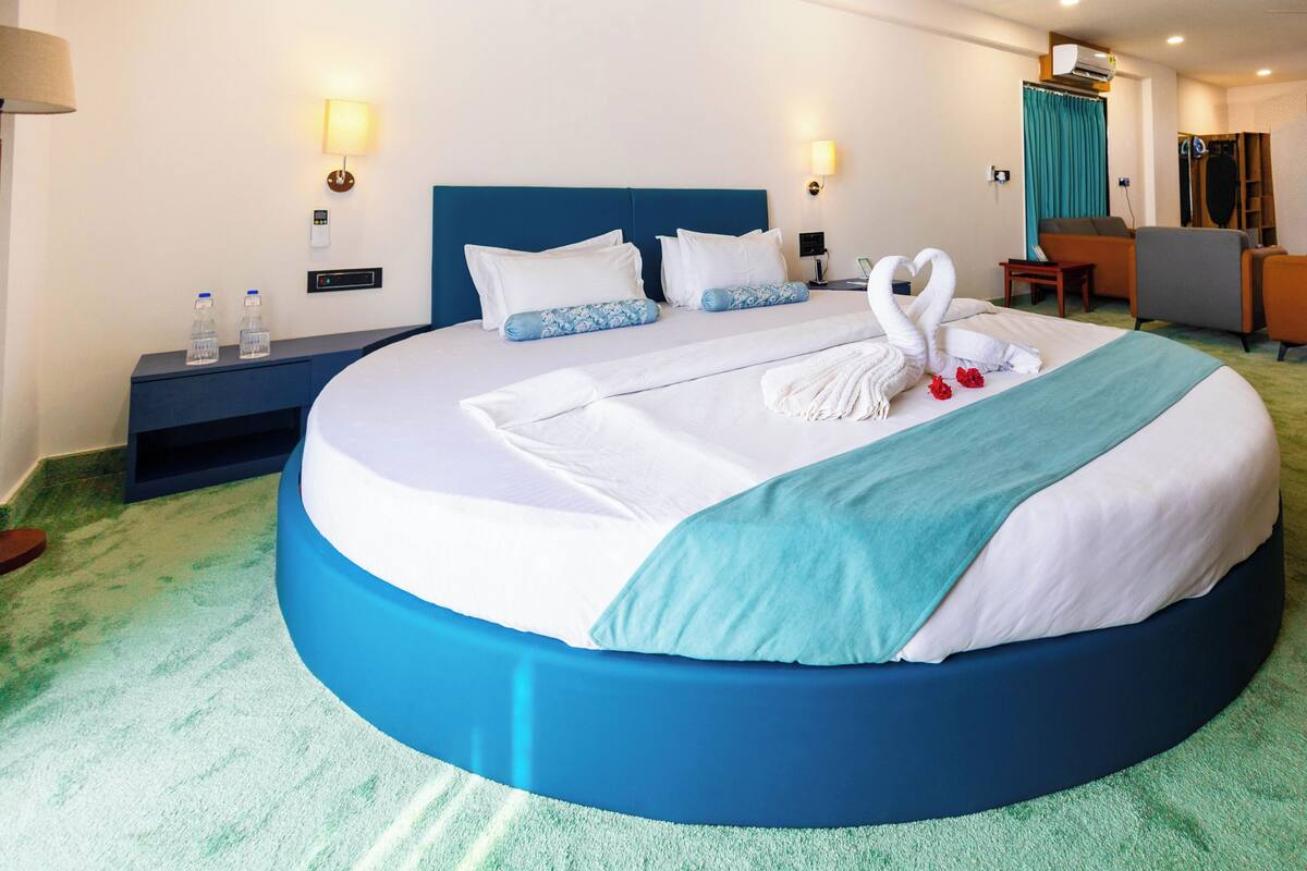 Ein Hotelzimmer mit einem Rundbett, einem Schreibtisch, einem Stuhl, einem Kleiderschrank und einem Badezimmer.