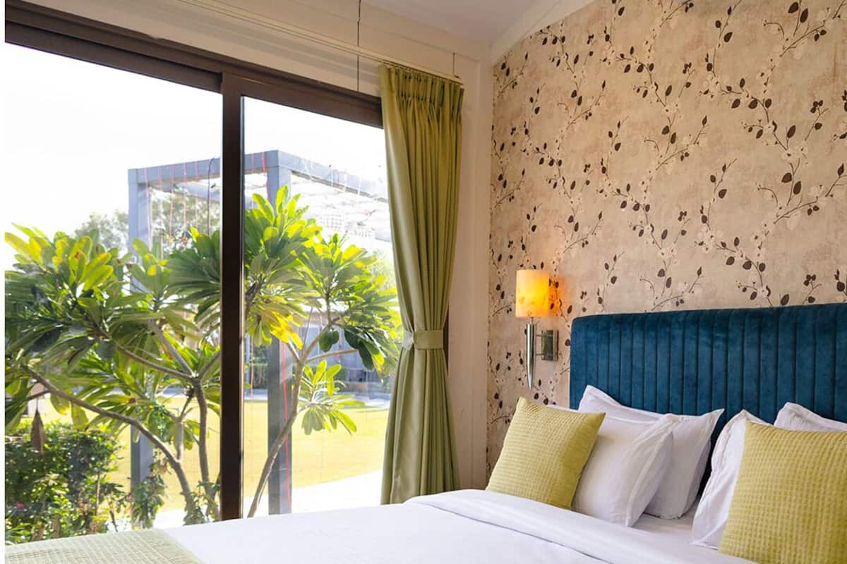 Ein Hotelzimmer mit einem großen Bett, Blick auf Grünfläche und einer Wand mit Muster.