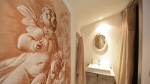 Een badkamer met een muurschildering van een cherubijn, een wastafel en een spiegel.