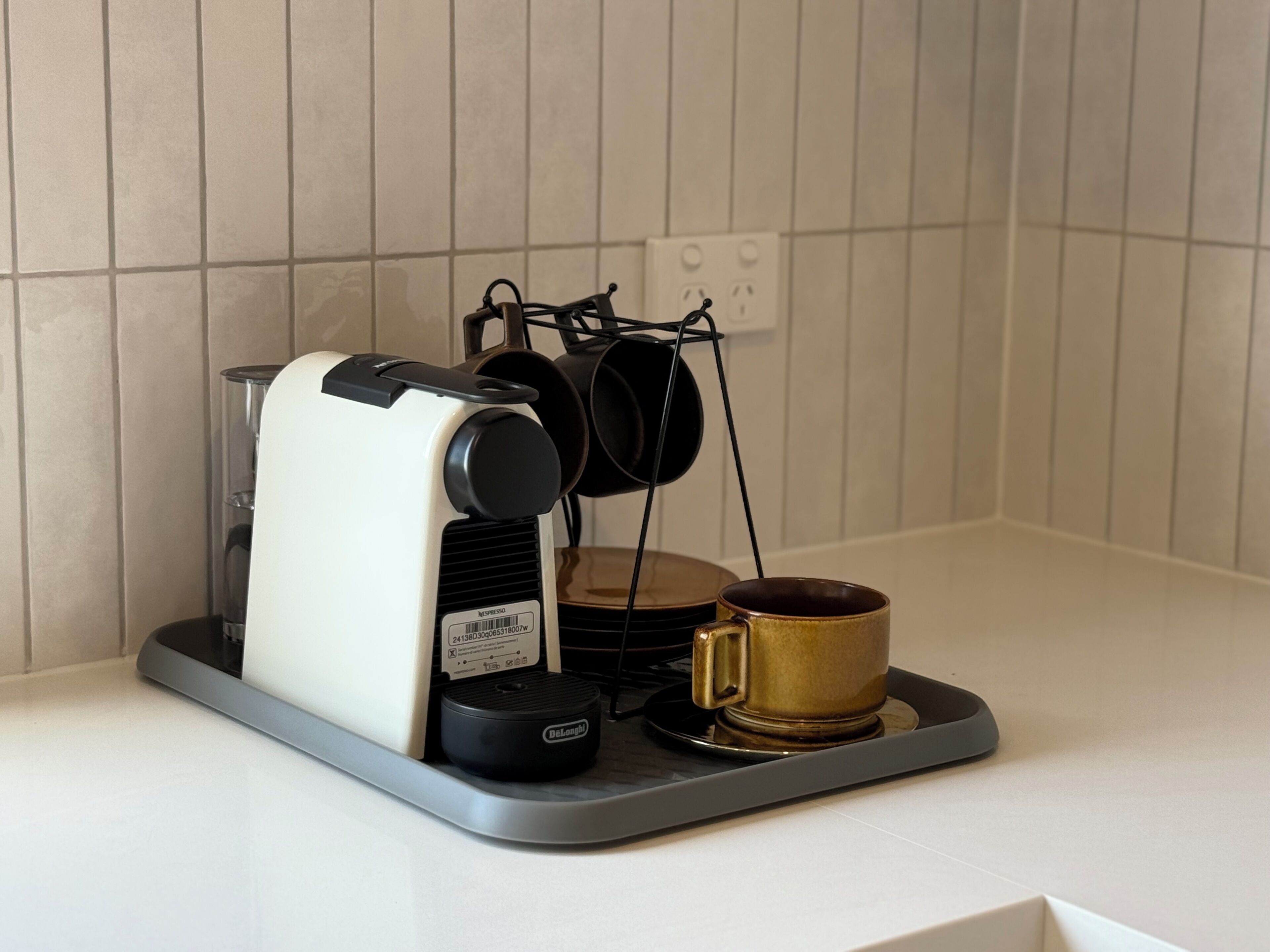 Una cafetera sobre una bandeja con una taza y una jarra.