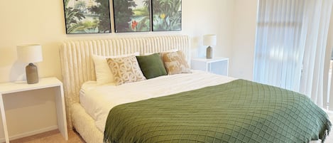 A neatly arranged bedroom with a large bed, two bedside tables, and a window with curtains.