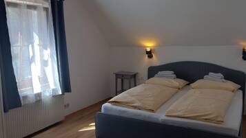 A bedroom with a bed, bedside tables, and a window with curtains.