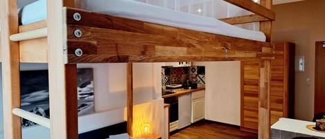 A compact room with a bunk bed, a small kitchenette, and a dining area.