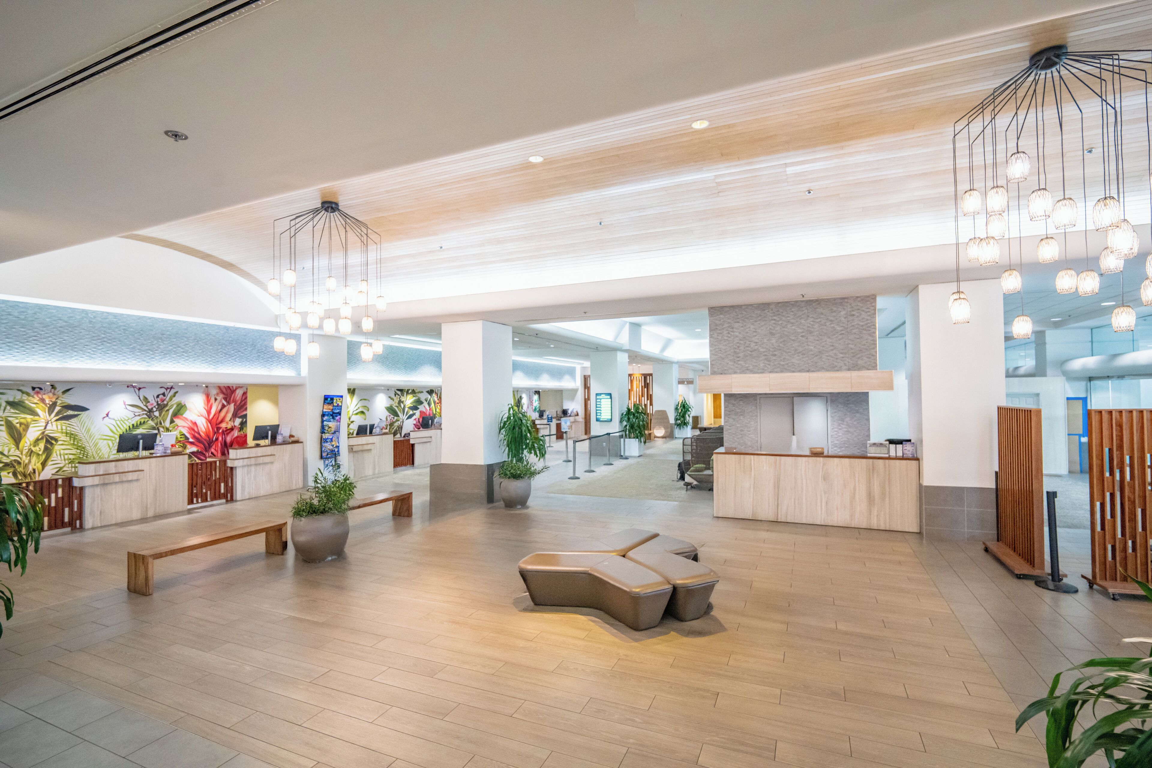 Un hall d’entrée spacieux avec un plancher en bois, un comptoir d’accueil, des espaces de détente et des luminaires modernes.