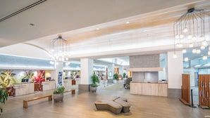 A spacious lobby with a wooden floor, a reception desk, seating areas, and modern lighting fixtures. - Junior Suite 1 Bedroom Ala Moana Condominium, City / Partial Ocean from Lanai (Honolulu)