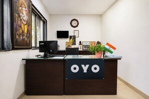 A reception desk with a sign that reads 'OYO,' a clock on the wall, and a framed picture of a deity. - Hotel O Ambuja City Centre Mall (Raipur)