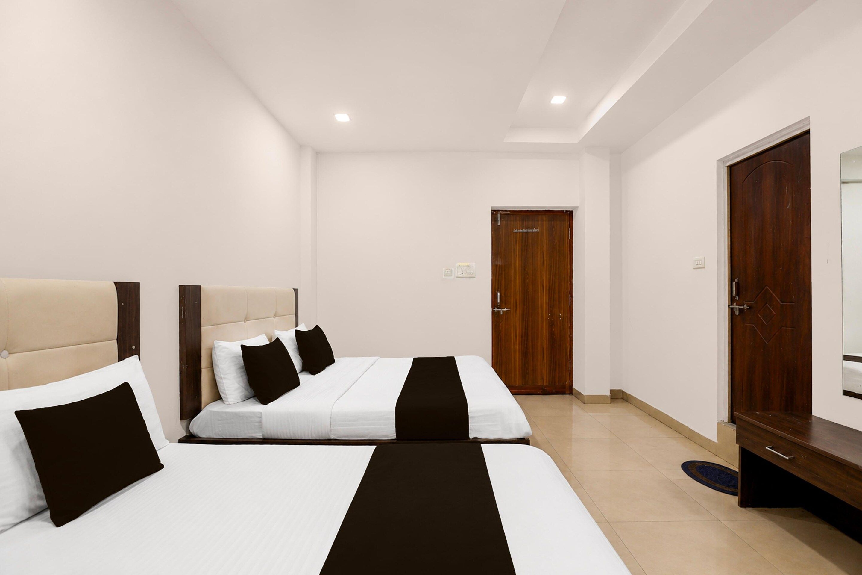 Una camera d'albergo con due letti, un armadio in legno e una porta.