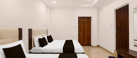 A hotel room with two beds, a wooden wardrobe, and a door.