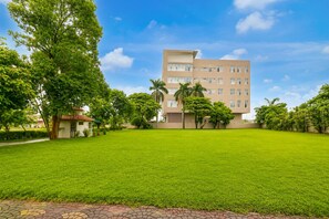 A multi-story building with a flat roof, surrounded by a well-maintained grassy area and trees. - Hotel O Ambuja City Centre Mall (Raipur)