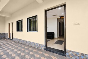 Un pasillo con piso estampado, un sofá negro y una puerta que da a una habitación con cama.