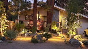 Una casa moderna con un giardino curato, un garage visibile e un vialetto.