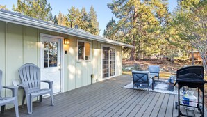 Una terraza de madera con mobiliario exterior y una parrilla.
