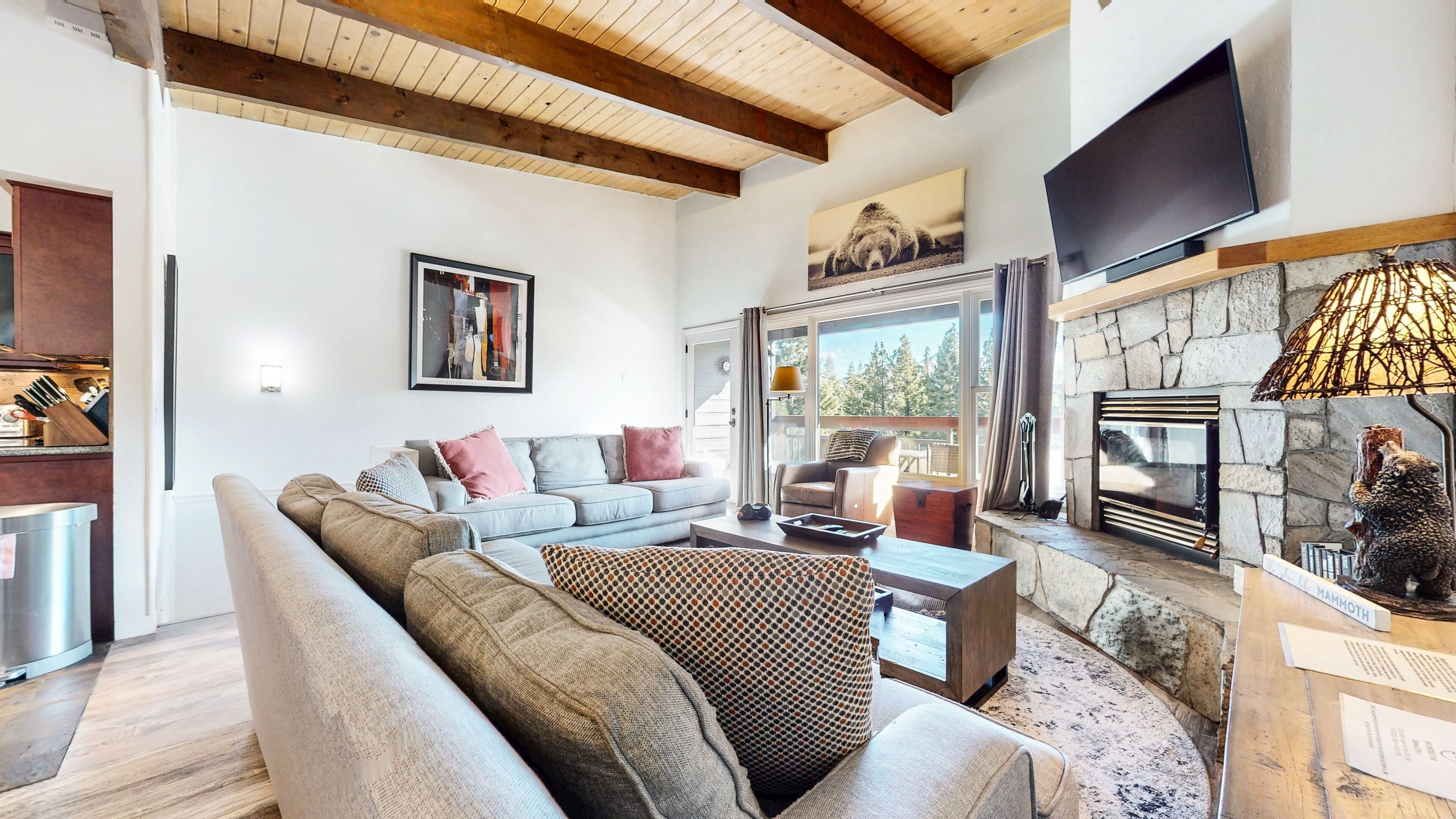 A cozy living room with a stone fireplace, a large flat-screen TV, and a comfortable seating area.