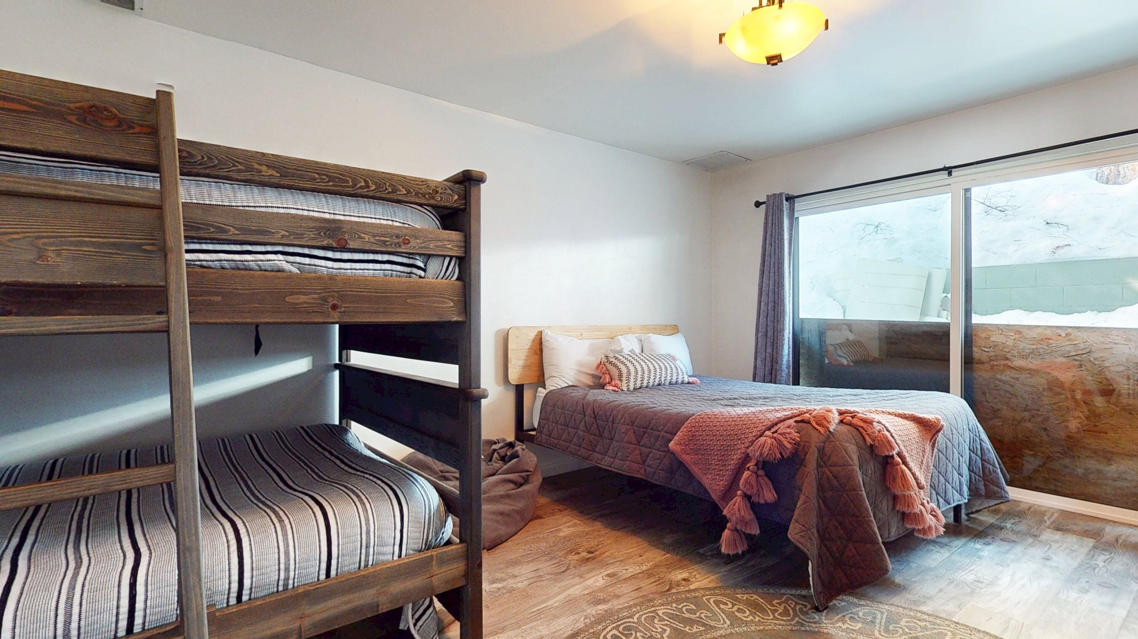 Une chambre avec un lit superposé, une fenêtre et une vue sur un paysage enneigé.
