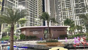 Un complejo residencial moderno con edificios altos, una plaza central con una fuente y palmeras.