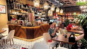 Un restaurante con mostrador de madera, diferentes platillos y luces colgantes.