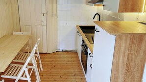 A compact kitchen with white cabinets, a wooden countertop, and a black faucet. - Charming half-timbered house in the heart of the city "Fachwerkstube" 3 Bedroom Apartment (Witzenhausen)