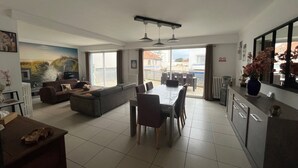 Un soggiorno moderno con divano, tavolo da pranzo e sedie. Una grande finestra offre vista all'esterno.