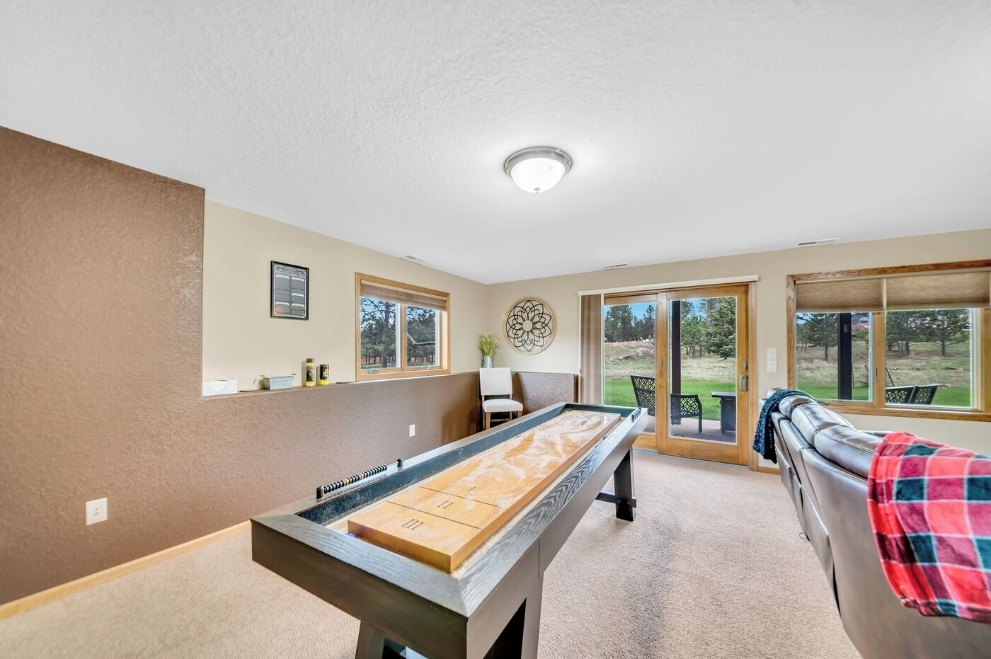 A pool table in a room with a sofa and a view of the outdoors.