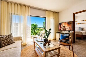 A hotel room with a sofa, a coffee table, a TV, and a balcony with a view.