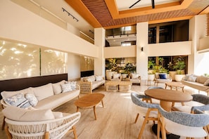 A spacious indoor area with multiple seating arrangements, including sofas and chairs, and a central coffee table.
