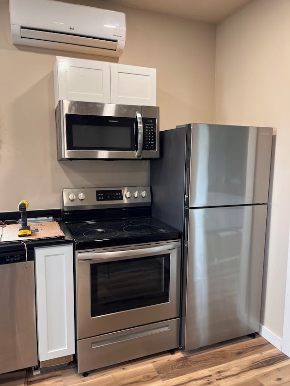 Una cocina compacta con microondas, horno y refrigerador de acero inoxidable.