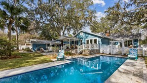 A poolside area with a pool, a covered patio, and a white picket fence. - King Bed • Pool • Chic • Kitchenette • Patio • FB 9 Min Walk • Beach 3 Min Drive (Fernandina Beach)