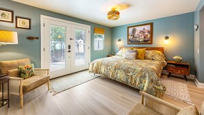 A bedroom with a large bed, a sofa, a side table, and a door leading to a balcony. - King Bed • Pool • Chic • Kitchenette • Patio • FB 9 Min Walk • Beach 3 Min Drive (Fernandina Beach)