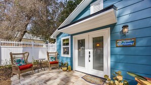 A house with a blue exterior, a white fence, and a patio with wicker furniture and potted plants. - King Bed • Pool • Chic • Kitchenette • Patio • FB 9 Min Walk • Beach 3 Min Drive (Fernandina Beach)