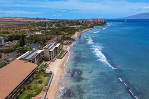 An aerial view of a coastal area with a beach, buildings, and a clear blue ocean. - Three bedroom right on the ocean with AC! (Lahina)