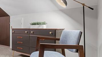 A modern room with a dark wooden dresser, a blue upholstered chair, and a floor lamp.