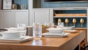 A dining table set with white plates, bowls, and glasses, with a wooden table runner. - Walk to Lambeau, Titletown & Resch • Park 4 Cars • Sauna & Tailgate Garage (Green Bay)