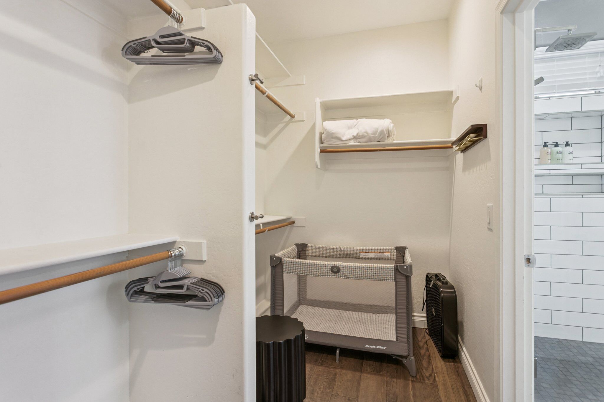 A compact bathroom with a shower, a towel rack, a small shelf with toiletries, and a baby changing station.