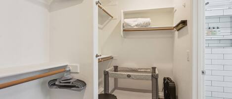 A compact bathroom with a shower, a towel rack, a small shelf with toiletries, and a baby changing station.