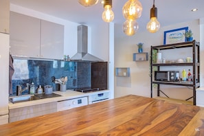 Eine moderne Küche mit einer Holztheke, Edelstahlgeräten und Pendelleuchten.