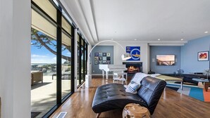 Una sala de estar moderna con un ventanal grande, una chimenea y un piano.