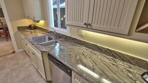 A kitchen with granite countertops, a double sink, and white cabinetry. - 4023 Monte Verde Sanctuary - Sweet Carmel Home (Carmel)
