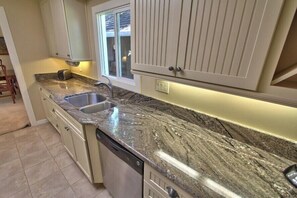 A kitchen with granite countertops, a double sink, and white cabinetry. - 4023 Monte Verde Sanctuary - Sweet Carmel Home (Carmel)
