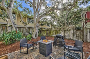 Une terrasse extérieure avec un foyer, des chaises et un barbecue.